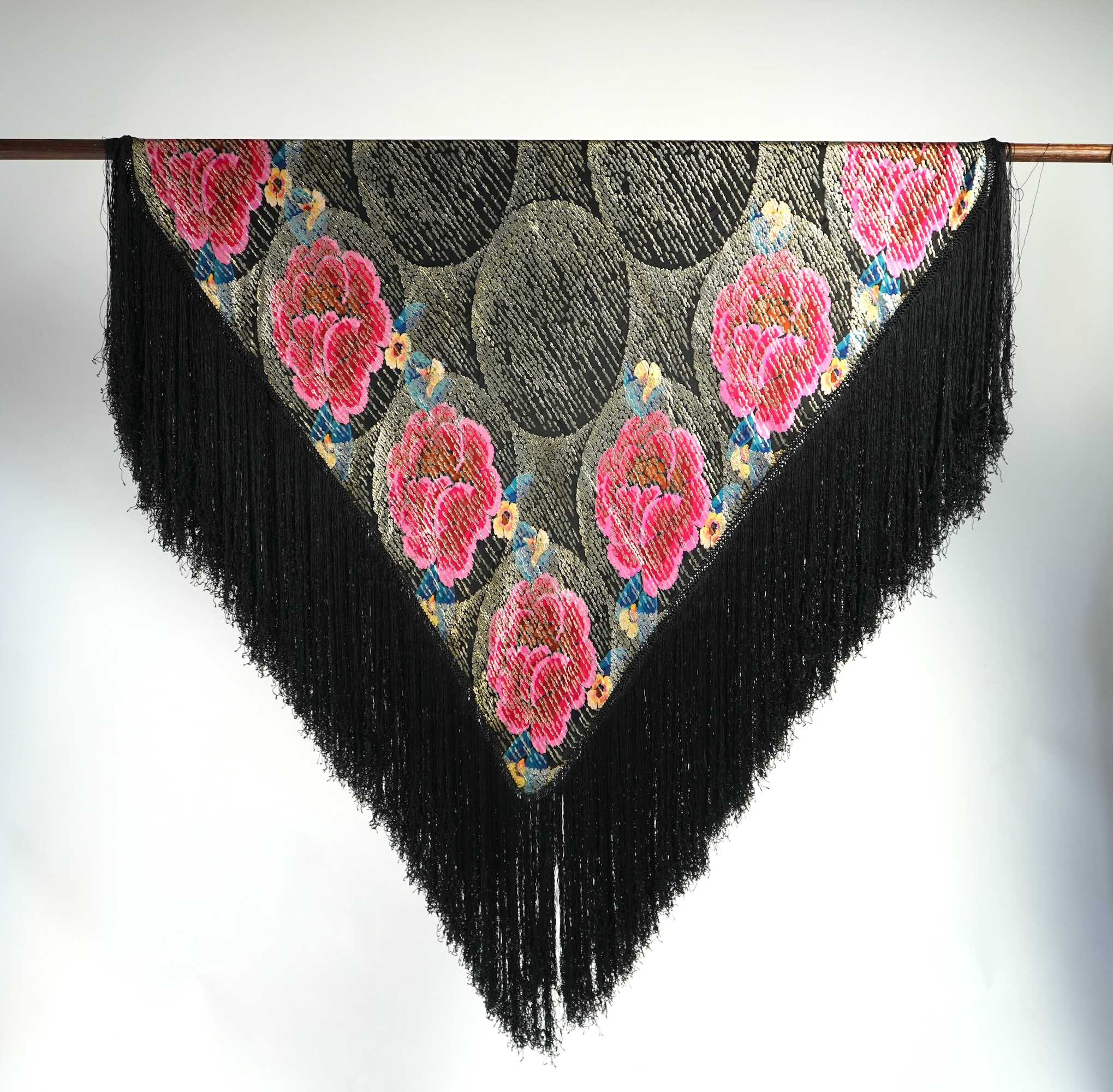 A 1930's ‘jazz age’ black and coloured silk lame evening shawl. Woven with giant pink and red roses and silver thread stripes, edged with long silk fringing. 118cm x 123cm. Condition - colours and silk strong. Fringing g